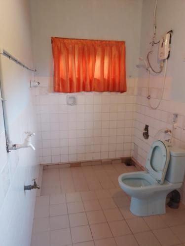 bagno con servizi igienici e tenda arancione. di Nehara Inn a Nuwara Eliya