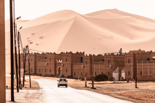 an old car driving down a road in front of a mountain at alimawragh in Merzouga