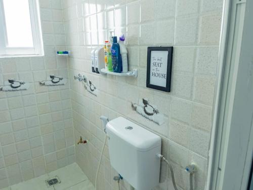 a white bathroom with a toilet and a sign on the wall at the cozy lookout in Malindi