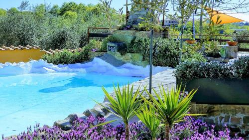 Un jardín con flores violetas y una piscina. en Piccolo Feudo Green Resort, en Viterbo