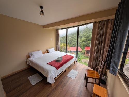 a bedroom with a bed and a large window at TUMI Villa Salkantay in Colcapampa