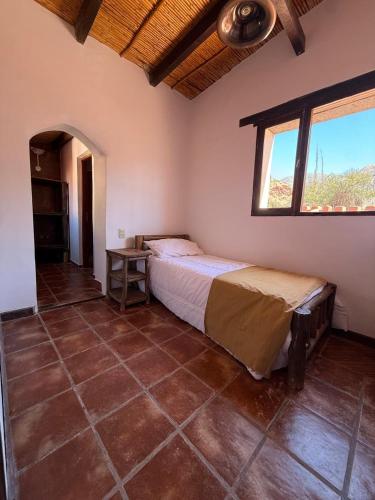 ein Schlafzimmer mit einem Bett in einem Zimmer mit einem Fenster in der Unterkunft El Patio in Purmamarca