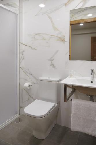 a white bathroom with a toilet and a sink at Pensión CasaBlanca in Arzúa