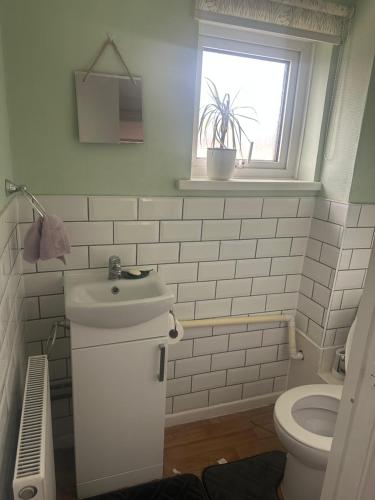 Un baño con lavabo, inodoro y ventana. en Newport by M4, en Newport