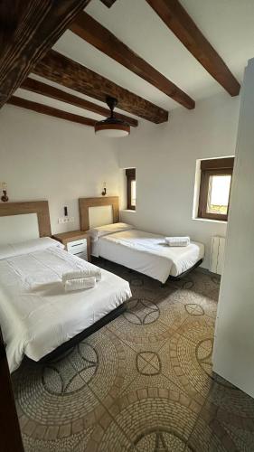 a bedroom with two beds and a rug at La Casa de los Testarros in Gavilanes