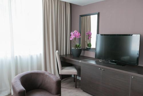 a room with a desk with a television and a chair at New City Hotel & Restaurant Niš in Niš