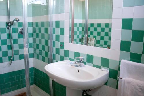 a green and white bathroom with a sink and a shower at Albergo Da Benedetta in Vetralla