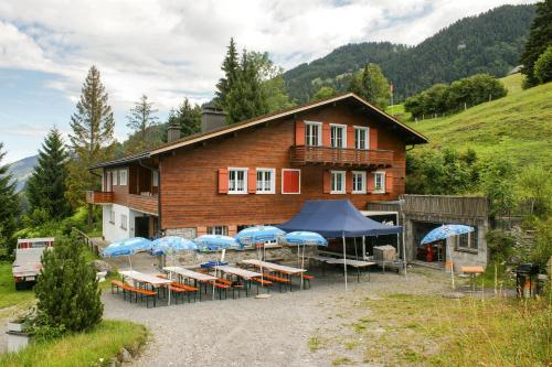 a building with chairs and umbrellas in front of it at Swiss Horizon-Gruppenhaus Mullern, vielseitiges Haus für Familien, Gruppen, Seminare und Gemeinschaft in Mollis
