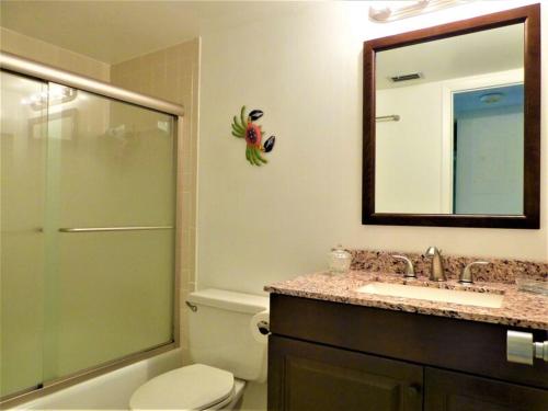 a bathroom with a toilet and a sink and a mirror at Midnight Cove II 128F in Siesta Key