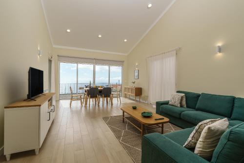 a living room with a green couch and a table at Villa Pargo Green by Madeira Dream Stays in Ponta do Pargo