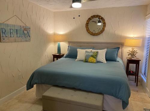 a bedroom with a bed with a blue comforter and a mirror at Midnight Cove II 212F in Siesta Key