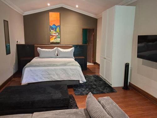 a bedroom with a large bed and a couch at The Nugget Guest Lodge in Kempton Park