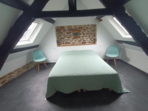 a bedroom with a bed and two chairs at Rêve et Rance in La Richardais