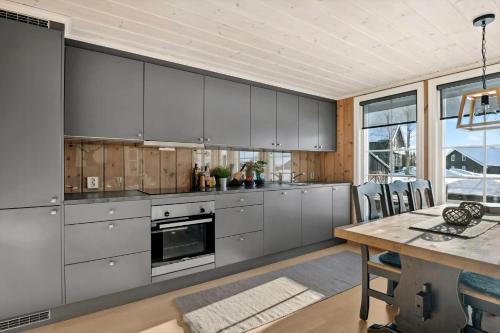 Una cocina con gabinetes grises y una mesa de madera. en Magical Winter Days At Sjusjøen, en Mesnali