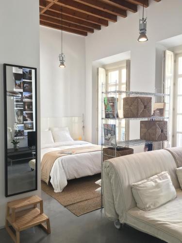 1 dormitorio con 2 camas, sofá y espejo en Suncity Ismo Arquitectura, en Málaga