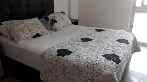ein Bett mit einer Bettdecke und Kissen darauf in der Unterkunft Espacio Confortable y Agradable, Atlantis in Santa Cruz de la Sierra