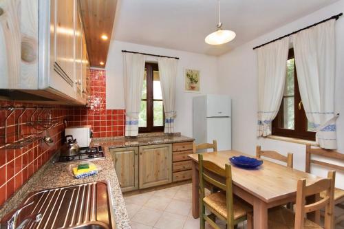 eine Küche mit Holztisch und ein Esszimmer in der Unterkunft Village surrounded by greenery with swimming pool just a few minutes from Alghero in Alghero