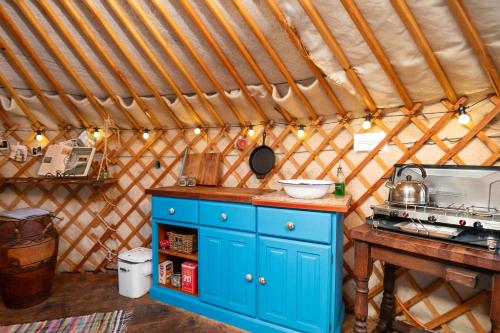 Eine Küche in einer Jurte mit einem blauen Schrank in der Unterkunft Finest Retreats - Pandy Traditional Yurt in Penmaen Pool