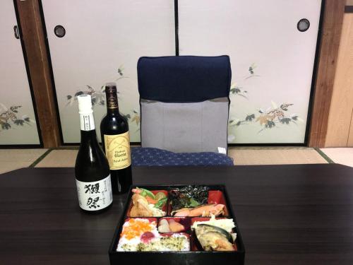 a table with a plate of food and a bottle of wine at YabFarm Lodge 101 in Kashiwa