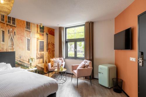 a bedroom with a bed and two chairs and a window at Boutique Hotel de Statie in Valkenswaard