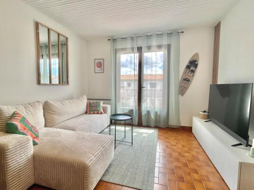 een woonkamer met een bank en een flatscreen-tv bij L'Echappée Salée - Close to center - Cozy in Longeville-sur-Mer