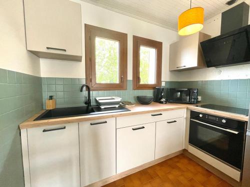 een keuken met witte kasten en een zwart apparaat bij L'Echappée Salée - Close to center - Cozy in Longeville-sur-Mer