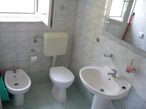 a white bathroom with a toilet and a sink at Apartmani Marija in Primošten