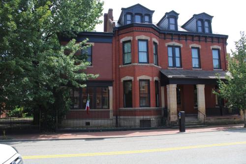 a large red brick house with a black fence at Villagio Boutique Hotel in Pittsburgh