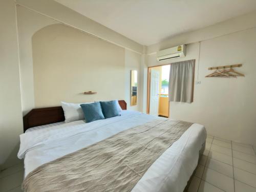 a bedroom with a large white bed with blue pillows at บ้านบี เซอร์วิส อพาร์ตเมนต์ in Si Racha
