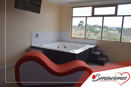 a bath tub in a bathroom with a window at Motel Sensaciones in Latacunga