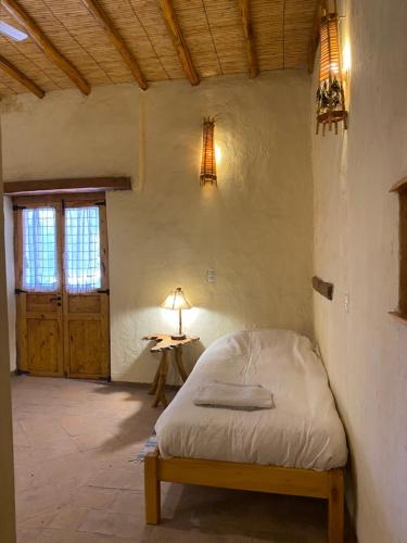 a bedroom with a bed and a table with a lamp at Pircas de Puyuta in San Juan