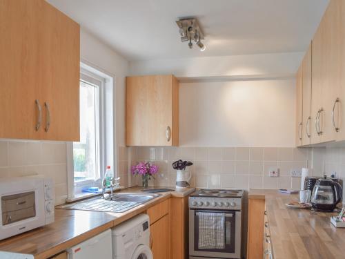 a kitchen with wooden cabinets and a stove top oven at Burnside Cottage in Bruichladdich