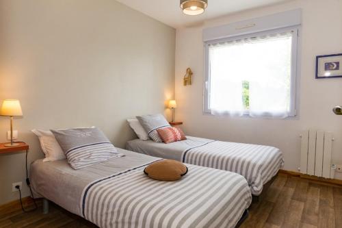 twee bedden in een kleine kamer met een raam bij Les hortensias in Grâces