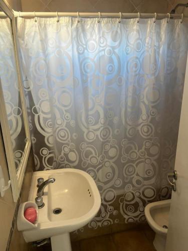 een badkamer met een wastafel en een douchegordijn bij Metro in Villa Gesell