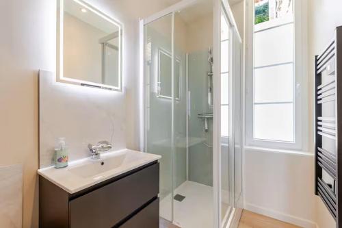 a white bathroom with a sink and a shower at Un des sens, vue port, Sauna et Spa in Le Tréport