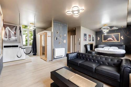 a living room with a black leather couch and a bathroom at Un des sens, vue port, Sauna et Spa in Le Tréport