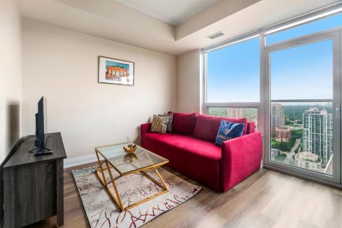 a living room with a red couch and a large window at High Floor 1 Bedroom plus Den Condo Apartment City View North York Toronto in Toronto