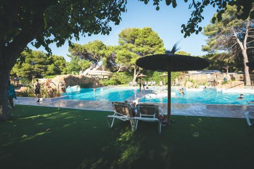 a swimming pool with two chairs and an umbrella at HolaCamp Sitges Garrofer in Sitges