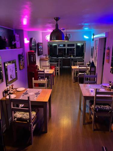 a restaurant with wooden tables and purple lights at The Southwold Guest House in Skegness