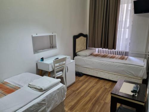 Habitación con 2 camas, escritorio y espejo. en Hotel Hoyuk, en Estambul