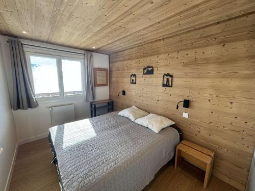 a bedroom with a bed and a wooden wall at Charmant 2 pièces 6 pers avec balcon sud, proche télé-siège et commerces à l'Alpe d'Huez - FR-1-405-3 in L'Alpe-d'Huez