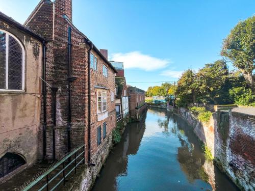 a view of a river between two brick buildings at The Knights Apartment, Eastbridge Hospital in Canterbury