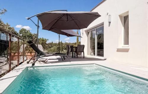 ein Swimmingpool mit Sonnenschirm neben einem Haus in der Unterkunft Maison Piscine Nîmes in Saint-Césaire