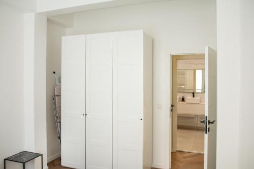 einen weißen Schrank in einem Zimmer mit Spiegel in der Unterkunft Brussels South - Cosy Appartment in Brüssel
