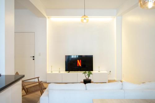 ein Wohnzimmer mit einem weißen Sofa und einem Fernseher in der Unterkunft Brussels South - Cosy Appartment in Brüssel