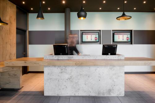 a lobby with a concrete counter with two chairs at ibis Genève Aéroport in Geneva