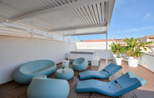 einen Balkon mit blauen Stühlen und Tischen auf einem Gebäude in der Unterkunft Cozy Apartment In Marina Di Ragusa With Wifi in Marina di Ragusa