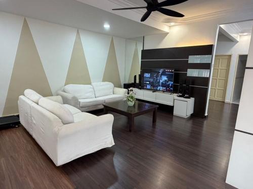 ein Wohnzimmer mit 2 weißen Sofas und einem TV in der Unterkunft Luxury 5Room 14pax Taman Desa Cermerlang in Ulu Tiram