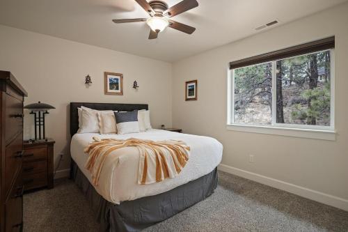 a bedroom with a bed with a ceiling fan and a window at Trails End Retreat in Bend