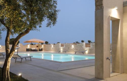 a swimming pool at night with benches and an umbrella at Lovely Home In Modica in Modica